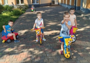 Dzieci jeżdżą na rowerkach i samochodzikach po tarasie