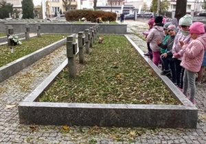Dzieci zapalają znicze na grobach żołnierzy i ofiar poległych w obronie ojczyzny