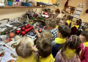 Dzieci zwiedzają fabrykę bombek i poznają kolejne etapy powstawnia tych ozdób świątecznych