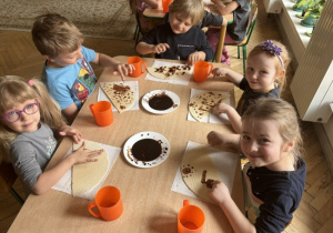 Dzieci wykonyją obrazek - rysowanie czekoladą na waflu