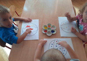 Dzieci malują farbami za pomocą paluszków.