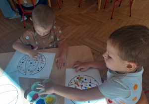 Dzieci malują farbami za pomocą paluszków.