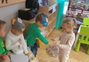 Dziewczynka wręczą chłopcom upominki.