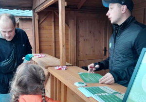 Dzieci z rodzicami uczestniczą w ekologicznej grze edukacyjnej.