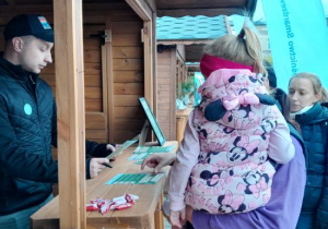 Dzieci z rodzicami uczestniczą w ekologicznej grze edukacyjnej.