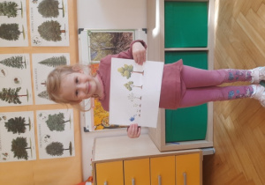 Dziewczynka trzyma plansze edukacyjną.