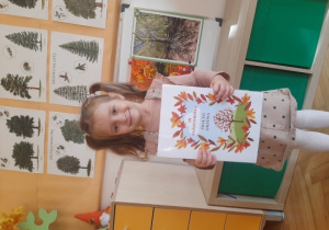 Dziewczynka trzyma plansze edukacyjną.