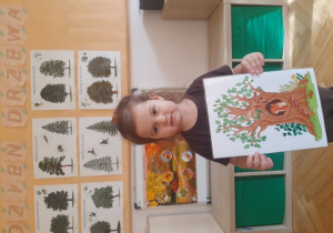 Dziewczynka trzyma plansze edukacyjną.