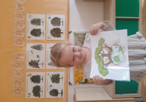 Dziewczynka trzyma plansze edukacyjną.