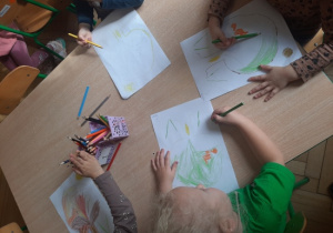 Dzieci malują drzewa kredkami.