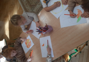 Dzieci malują drzewa kredkami.