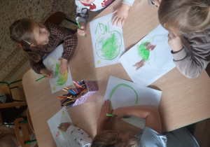 Dzieci malują drzewa kredkami.