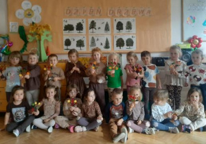 Pamiątkowe zdjęcie grupowe z drzewkami wykonanymi przez dzieci.
