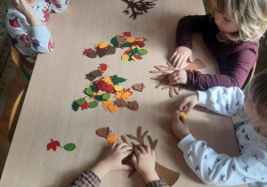 Dzieci dekorują filcowe drzewka.