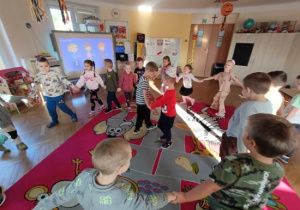 Dzieci tańczą w kole i śpiewają koledze 100 lat.