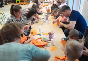 Rodzice i dzieci tworzą papierowe dynie.