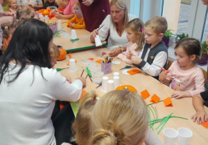 Rodzice i dzieci tworzą papierowe dynie.