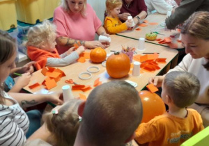Rodzice i dzieci tworzą papierowe dynie.