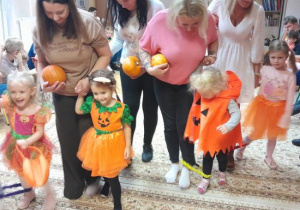 Rodzice i dzieci uczestniczą w zabawach ruchowych z dynią.