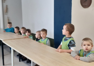 Dzieci stoją przy stołach.