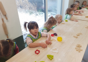 Dzieci przy użyciu foremek wykrawają pierniczki.