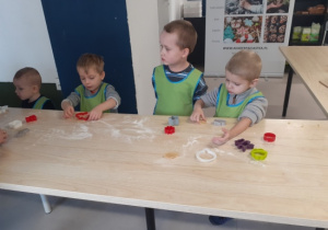 Dzieci przy użyciu foremek wykrawają pierniczki.