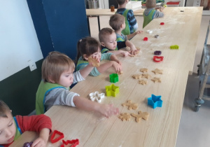 Dzieci przy użyciu foremek wykrawają pierniczki.