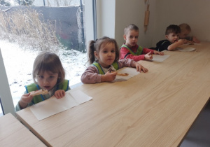 Dzieci jedzą pizzę.