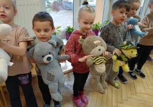 Dzieci wykonują misiową gimnastykę ze swoimi pluszakami.