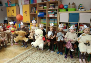 Dzieci wykonują misiową gimnastykę ze swoimi pluszakami.