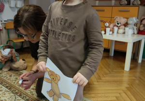 Dziewczynka wykleiła misia wg wzoru.