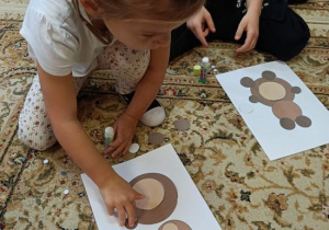 Dzieci biorą udział w zadaniu: wyklejanie misia wg wzoru.