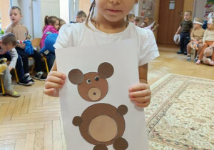 Dziewczynka wykleiła misia wg wzoru.