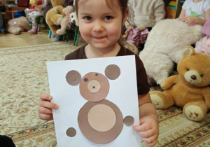 Dziewczynka wykleiła misia wg wzoru.