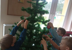 Dzieci ubierają choinkę.