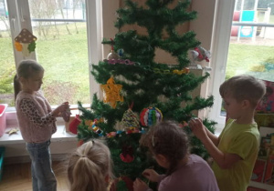 Dzieci ubierają choinkę.