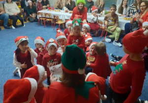 Dzieci i rodzice biorą udział w spotkaniu mikołajkowym.