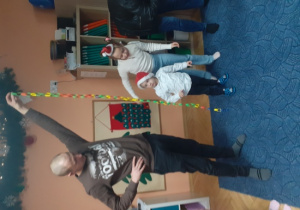 Dzieci i rodzice biorą udział w spotkaniu mikołajkowym.