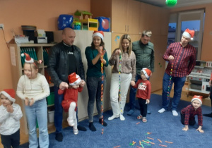 Dzieci i rodzice biorą udział w spotkaniu mikołajkowym.