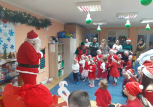Dzieci i rodzice biorą udział w spotkaniu mikołajkowym.