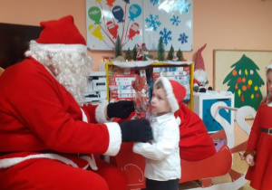 Dzieci i rodzice biorą udział w spotkaniu mikołajkowym.