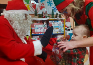 Dzieci i rodzice biorą udział w spotkaniu mikołajkowym.