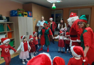 Dzieci i rodzice biorą udział w spotkaniu mikołajkowym.