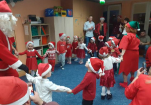 Dzieci i rodzice biorą udział w spotkaniu mikołajkowym.