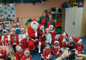 Dzieci i rodzice biorą udział w spotkaniu mikołajkowym.