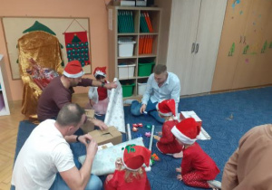 Dzieci i rodzice biorą udział w spotkaniu mikołajkowym.