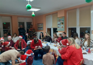 Dzieci i rodzice biorą udział w spotkaniu mikołajkowym.