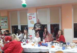 Dzieci i rodzice biorą udział w spotkaniu mikołajkowym.