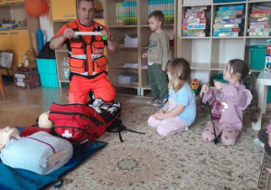 Dzieci uczestniczą w spotkaniu z ratownikiem medycznym.