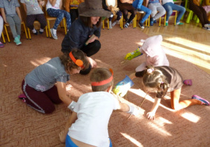 Dzieci biorące udział w konkursie podnoszenia patyczków przez rękawice kuchenne